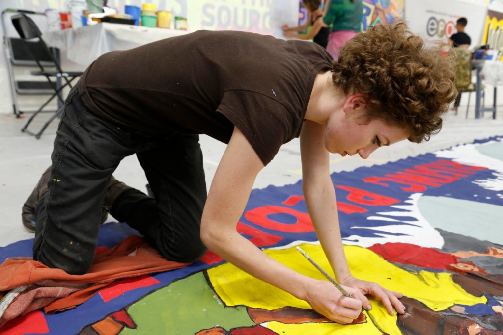 Sarah Quinter draws on a large banner in Mayday Space. Photography by Wen Xin
